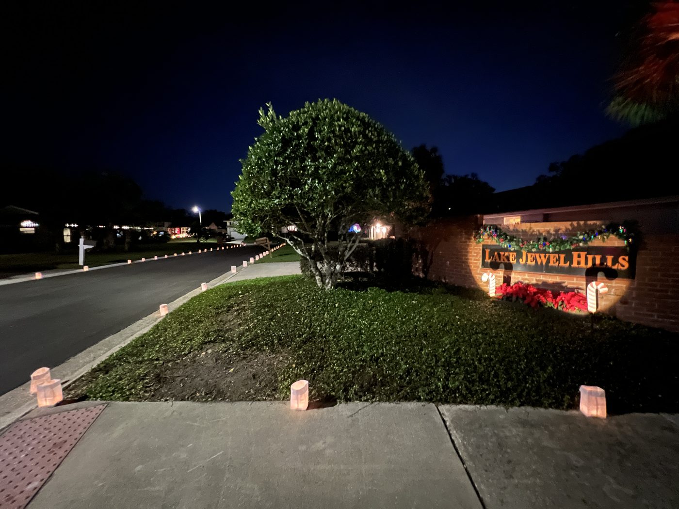 Lake Jewel Hills entrance decorated with luminaries and holiday lights at night